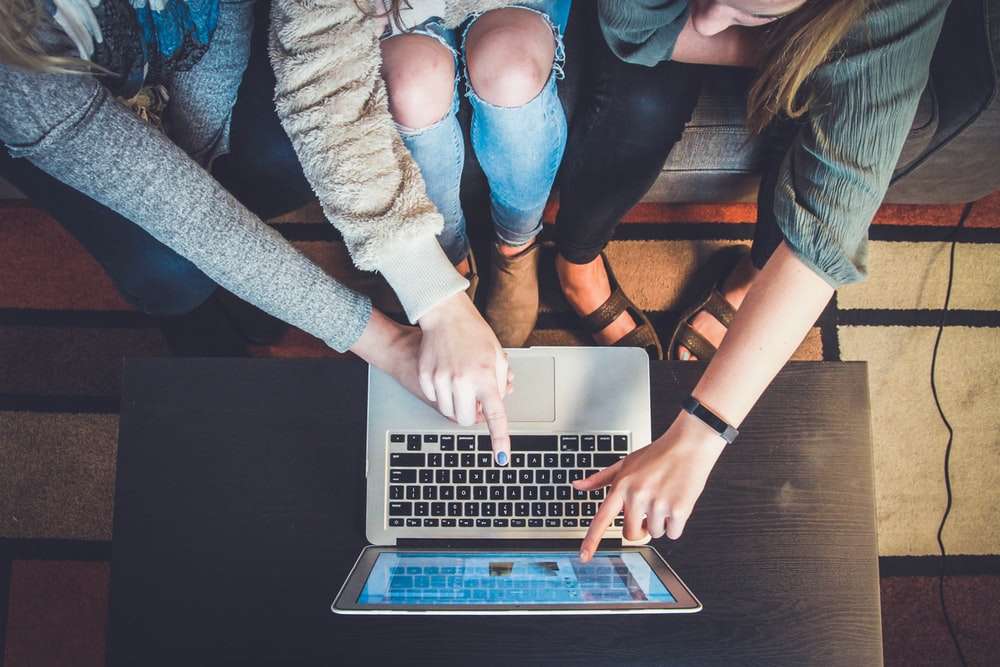 three person pointing the silver laptop computer